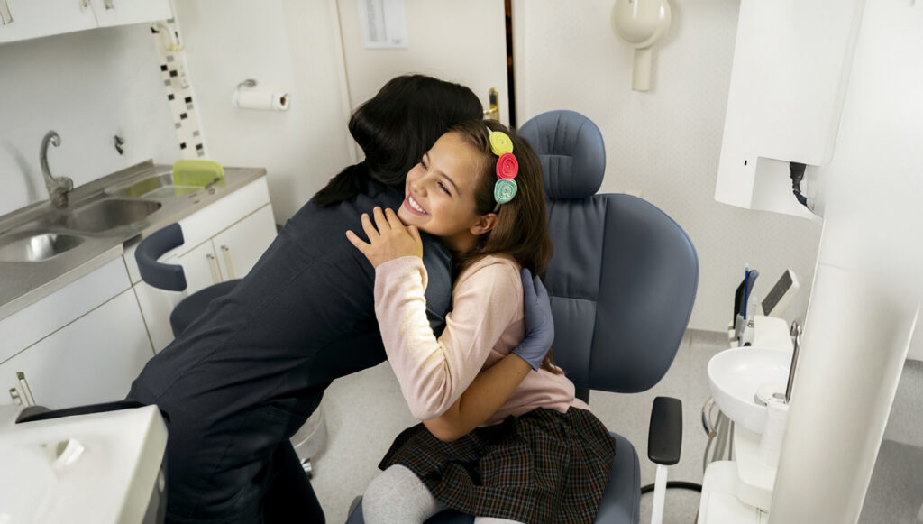 Happy Girl Patient Being Huged By A Nurse In Black Scrubs